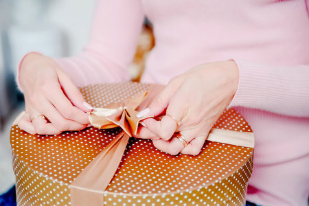 A woman ties a box with a gift. Gift packaging.の写真素材