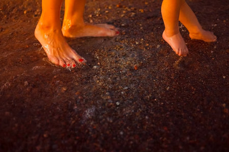 The legs of the baby and mother on the beach. Swimming in the sea with a child.の写真素材