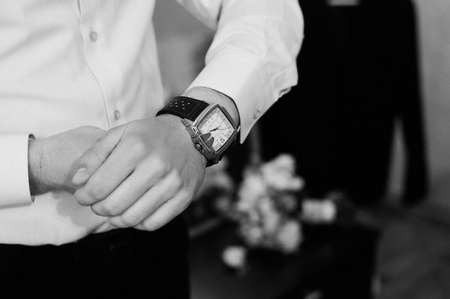 A man in a shirt looks at a wristwatch.の写真素材