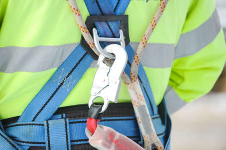 The hook of the safety carabiner attached to the safety belt is worn on the worker.の写真素材