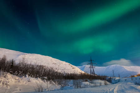 Northern Lights over snow-capped hills.の写真素材