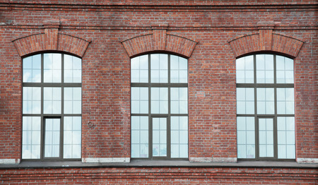 Three windows on the red old-fabric bric wallの写真素材