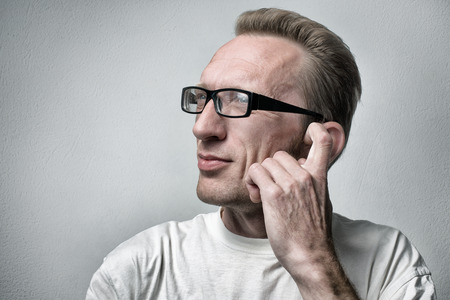 Thinking man on gray textured background  Closeup portrait of a casual young pensive businessman looking up at copy space and itch his ear の写真素材