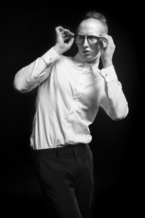 Fashion man model looks like nerd or hipster from horror, white shirt, eyeglasses and black trousersの写真素材