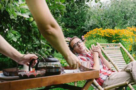 Man drinking tea in his own garden at summer day