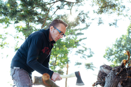 Man cutting wood with axe in the evening forest.の写真素材