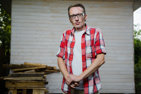 confident 30-40 years old farmer stand on his back yard and lean on the spade handleの写真素材