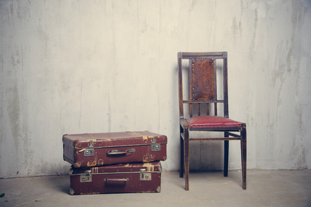 two old suitcases and the old leather chair near the gray textured wallの写真素材