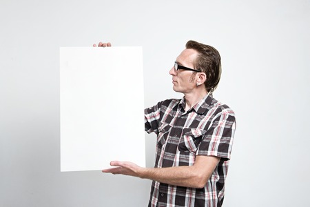 Man in eyeglasses and tartan shirt displaying a white boardの写真素材