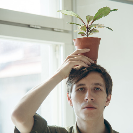 man keep a pot with plant on his head. ecological conceptの写真素材