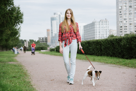 Pretty long hair girl walking her dog on a leashの写真素材