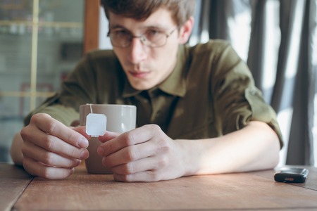 sad man drinking tea on the wooden tableの写真素材