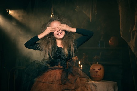 small girl in witch costume sit on the tableの写真素材