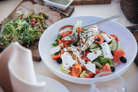 greek salad on white plate at the tableの写真素材