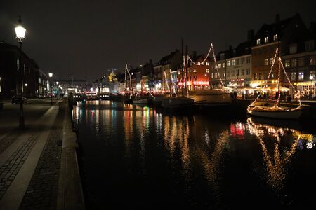 Nyhavn is an old port, canal and vacation spot in Copenhagen, Denmark. Ships, festive illumination, reflection in the dark water of the canal. Lanterns. Walking through the evening Copenhagen. Travel, Tourismの写真素材