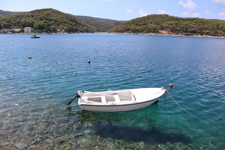 Calm clear water of the sea, mountains overgrown with pines, motorboat against the background of turquoise water on the Adriatic coast, island of Brac, Croatiaの写真素材