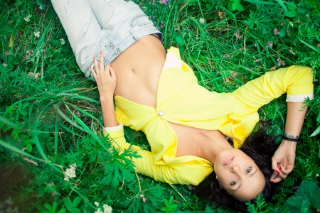 Yang beautiful girl lying on a grassの写真素材