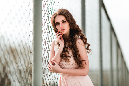 Sensual girl in pink dress near the fenceの写真素材