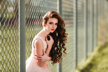 Sensual girl in pink dress near the fenceの写真素材