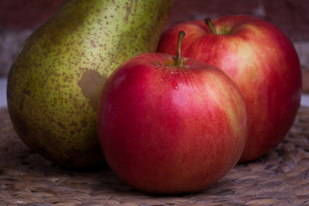 Green pear and red apple on a background wall.の写真素材