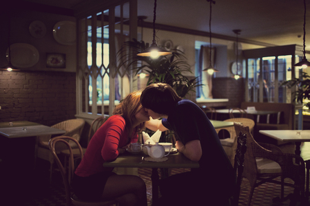 man is kissing woman sitting at restaurantの写真素材
