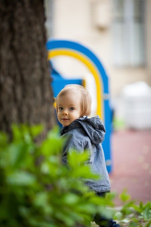 Small boy playing outside. Portrait of 2 year old toddler with blond hair and blue eyes.の写真素材