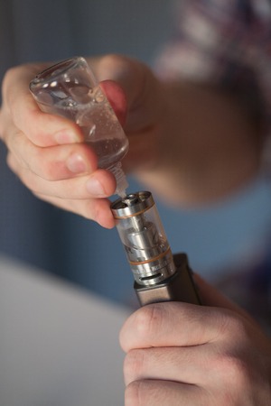 Man fills in the electronic cigarette liquid for evaporation.の写真素材