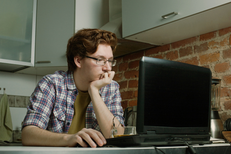 Young man sitting at a laptop and thinks about problem solving.の写真素材
