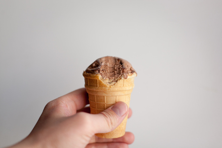 Waffle cup with chocolate ice cream in a hand on a white background.の写真素材