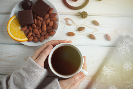 Women's hands holding a cup of coffee on a wooden table. top viewの写真素材