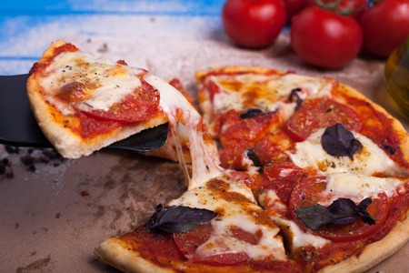 A slice of homemade Italian pizza with mozzarella, Basil and tomatoes. Vegetarian food.の写真素材
