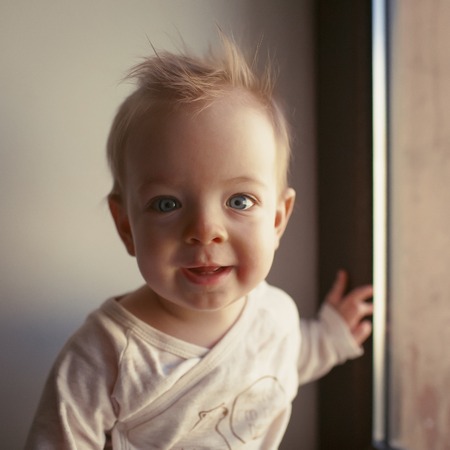 Portrait of a little boy who is sitting in the window and smiling. emotions conceptの写真素材