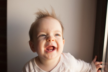 Portrait of a little boy who is sitting in the window and smiling. emotions conceptの写真素材