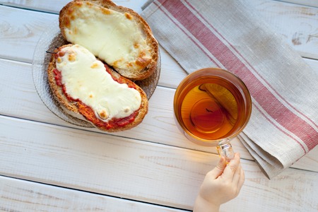 The hand of a little boy who is holding a mug of tea. Breakfast concept.の写真素材