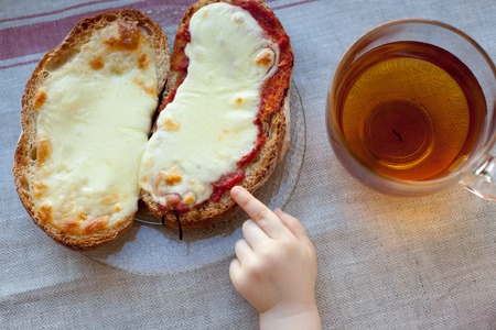 The hand of a little boy who is trying to steal my father's sandwich with tea. Breakfast concept.の写真素材