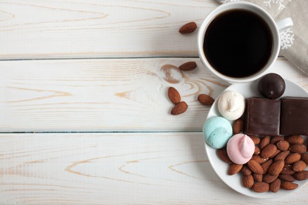 Black coffee with sweets and almonds on wooden background. Copy space. Top view.の写真素材