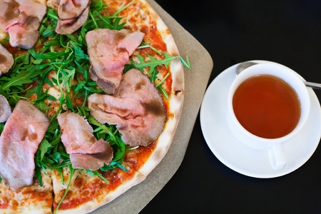 Pizza with roast beef and rocket salad on a table.の写真素材
