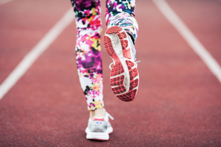 Close up of girls feet in sneakers and tights, running on a special running track with a soft finish.の写真素材
