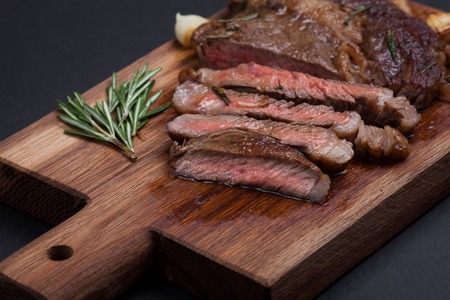 Grilled ribeye steak of marble beef closeup with spices on a wooden Board. Juicy steak medium sliced and ready to eat. With copy space. Top viewの写真素材