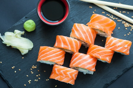 Philadelphia roll classic on a dark stone background. Philadelphia cheese, cucumber, avocado....