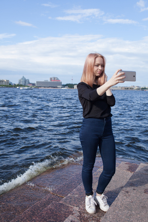 Young cute girl makes selfie on the waterfront of St. Petersburgの写真素材