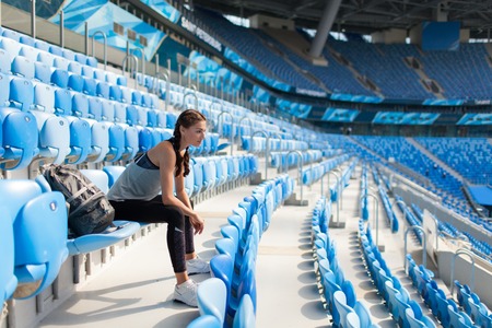 Sexy sport girl posing at stadium with the backpack. Fitness girl with a sports figure in black...