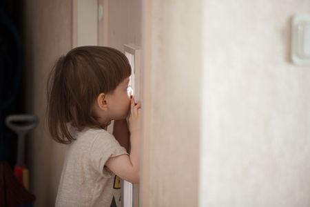 The little boy looks in the window of the door. A child spying on his parents from behind the closed bedroom doorの写真素材