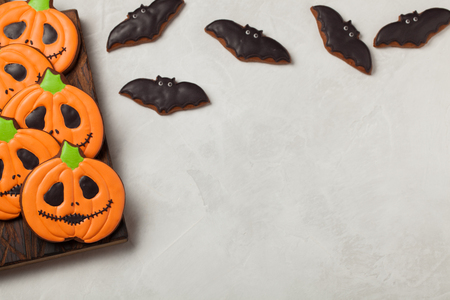 Homemade ginger cookies in the shape of pumpkins and bats on Halloween. On the lighter concrete background. Top view with copy spaceの写真素材