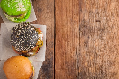 Set of three mini homemade Burger with marble beef and vegetables on a old wooden background. the concept of junk food and fast food. Top View with copy space.の写真素材