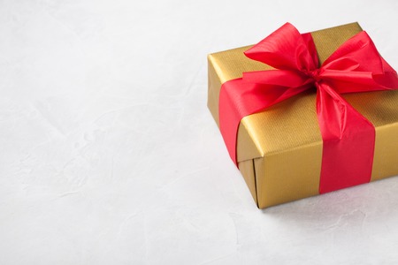 Golden gift box tied with a red ribbon isolated on white background. Copy space.