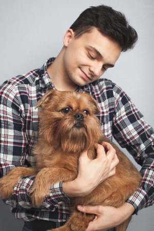 Closeup portrait handsome young hipster man, kissing his good friend red dog isolated light background. Positive human emotions, facial expression, feelings.の写真素材