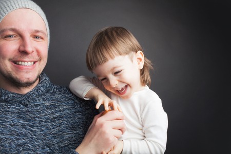 Dad plays with a lovely little son, sitting on his hands on a black background in the studio. It amuses it with Apple and they both laugh. Photos to celebrate father's day.の写真素材