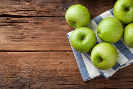 Ripe green apples in a wooden bowl on an old rustic table. Useful fruits on wooden background. Top view with copy space.の写真素材