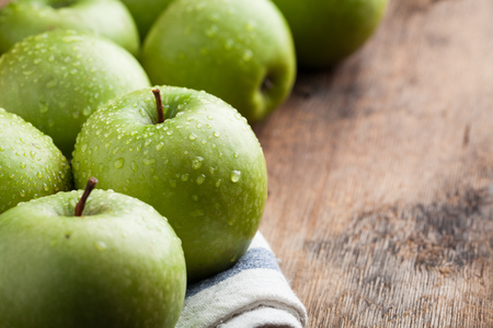 Ripe green apples in a wooden bowl on an old rustic table. Useful fruits on wooden background. with copy space.の写真素材
